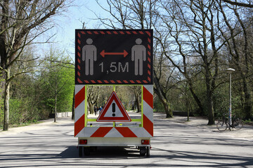 sign in park with warning to keep distance