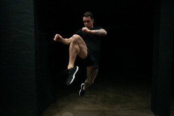 Kickboxer practicing kicks in dark gym