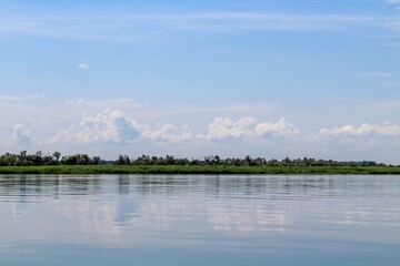 Calm water with a reflection of the sky and a strip of greenery on the horizon