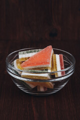 Colorful jelly candy in the glass bowl on wooden background. Multi-colored marmalade jelly candy's. Heap of triangular marmalade candy.