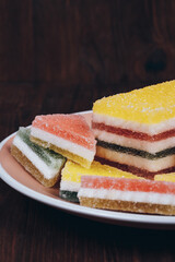 Colorful jelly candy in the plate on wooden background. Multi-colored marmalade jelly candy's. Heap of triangular and rectangular  marmalade candy.