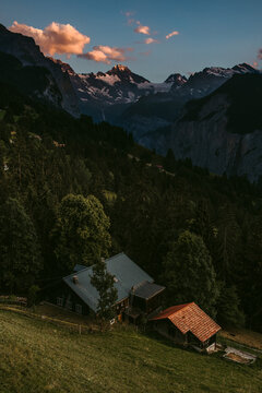 Distant cottages next to forest and high mountains