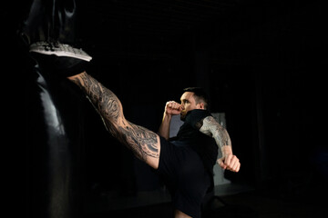 Professional kickboxer kicking bag in gym