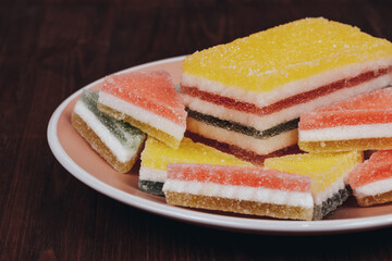 Colorful jelly candy in the plate on wooden background. Multi-colored marmalade jelly candy's. Heap of triangular and rectangular  marmalade candy.