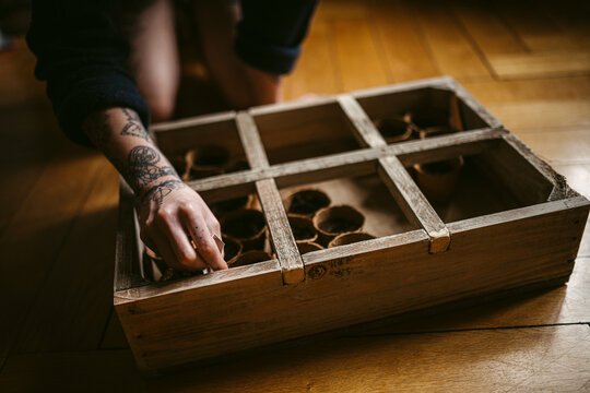 Crop anonymous gardener preparing seedlings in wooden box in flat