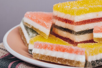 Colorful jelly candy in the plate at checkered napkin on grey background. Multi-colored marmalade jelly candy's. Heap of triangular and rectangular  marmalade candy.
