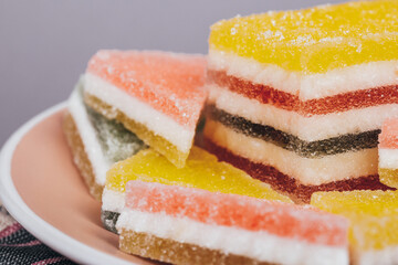 Colorful jelly candy in the plate at checkered napkin on grey background. Multi-colored marmalade jelly candy's. Heap of triangular and rectangular  marmalade candy.