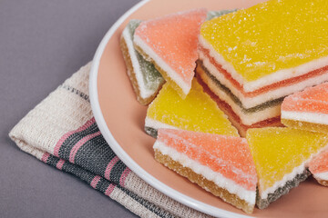 Colorful jelly candy in the plate at checkered napkin on grey background. Multi-colored marmalade jelly candy's. Heap of triangular and rectangular  marmalade candy.