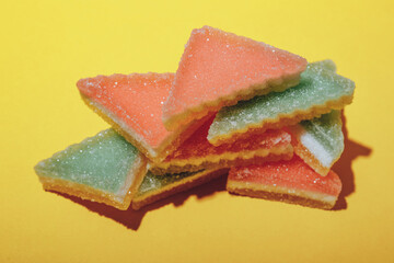 Heap of triangular marmalade candy on yellow background. Multi-colored marmalade jelly candy's. 