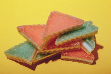 Heap of triangular marmalade candy on yellow background. Multi-colored marmalade jelly candy's. 