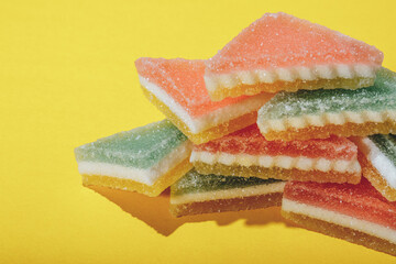 Heap of triangular marmalade candy on yellow background. Multi-colored marmalade jelly candy's. 