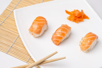 Rice and salmon nigiri on white plate and white background.