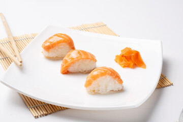 Rice and salmon nigiri on white plate and white background.