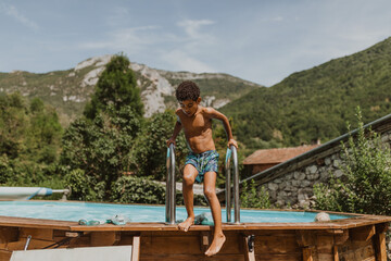 African American boy going down the pool ladder