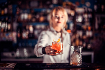 Girl barman makes a cocktail at the saloon