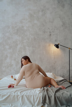 portrait of an Asian woman in a swimsuit sitting on a bed with her back to the camera