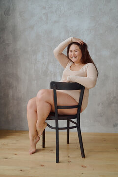 Beautiful Woman shows off full figure In Underwear sitting on a black chair