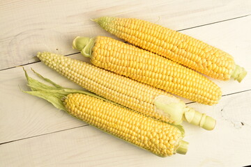 Ripe corn cobs, close-up, on a wooden table.
