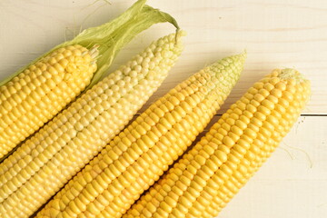 Ripe corn cobs, close-up, on a wooden table.