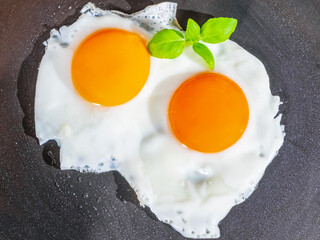 Two freshly fried eggs in frying pan, beautiful egg yolk, mouthwatering food