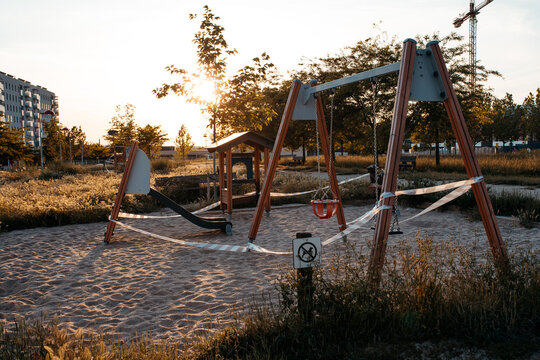 Swings in playground with white and red signaling tape to prohibit the passage