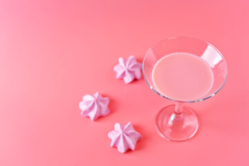 Pink milk cocktail in a glass with merengue cookies