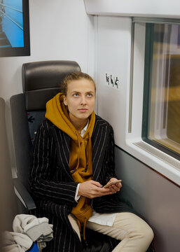 woman with a bagpack and Luggage is sitting on a high-speed train to the airport. she holds a smartphone in her hands and writes to her parents and friends that she is flying home