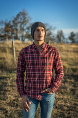 portrait of a 30 year old man in a red checkered shirt and gray wool hat