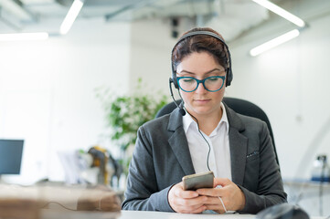 The call center operator gets bored and uses a smartphone at the workplace. A business woman is...