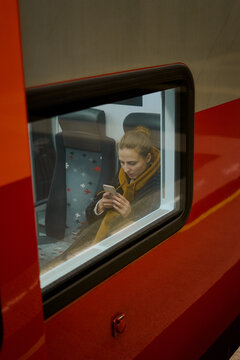 woman with a bagpack and Luggage is sitting on a high-speed train to the airport. in the hands of holds smartphone and downloads the map and travel programs apps