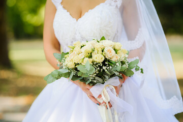 Wedding bouquet of white roses in the hands of the bride