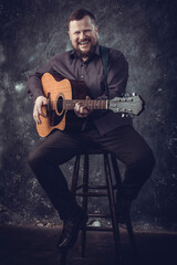 Obraz premium Mature musician plays acoustic guitar emotional studio portrait.