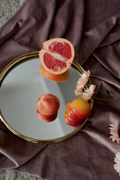 still life on the concrete floor draped in velvet fabric and mirror, slice grapefruit and peaches