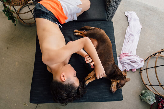 Young boy laying with small dog.