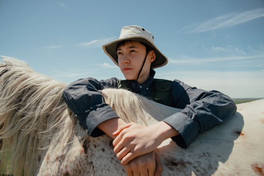Portrait of an Asian guy with a white horse