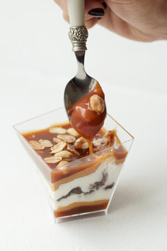 a woman's hand breaks off a piece of dessert with caramel, nuts, chocolate and nougat