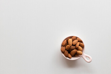 Fresh almonds nuts in pink plate on white background. Flat lay, top view, copy space.