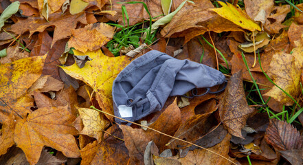 A lost medical face mask lies on an autumn-colored background Coronavirus Covid-19 epidemic