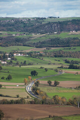 Fototapeta na wymiar Car road crossing the agricultural fields, hills and forests in the autumn