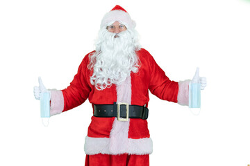 Santa Claus wearing a covid medical mask, holds mask or respirators epidemic or coronavirus protection. Santa shows thumb finger up