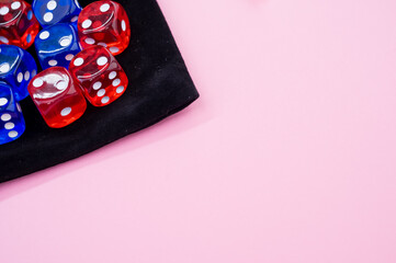 Top view of red and blue dice on a dice bag isolated on light pink background