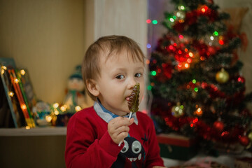 Child opening present at Christmas tree at home.  Little baby boy sweet. Surprise, celebration.