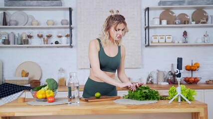 portrait young fitness woman blogger records video vlogs for making detox or healthy drink at home in the kitchen Attractive sports fitness girl online with mobile phone camera prepares in the kitchen