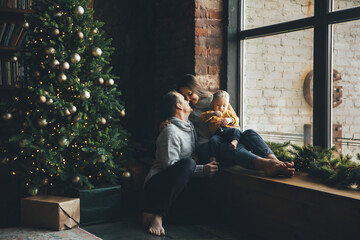 Naklejka premium Happy family at home in cozy living room with a decorated festive Christmas tree