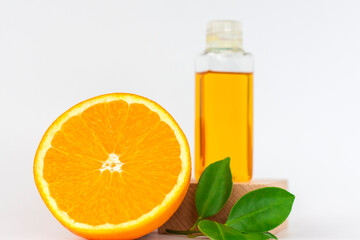 Orange oil for the body. Orange on a wooden pedestal on a white background. Organic SPA cosmetics with herbal ingredients.