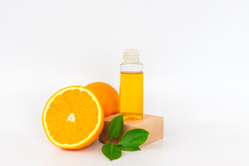 Orange oil for the body. Orange on a wooden pedestal on a white background. Organic SPA cosmetics with herbal ingredients.