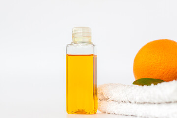 Orange oil for the body. Orange on a towel and on a white background. Organic SPA cosmetics with herbal ingredients.