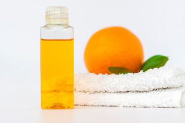 Orange oil for the body. Orange on a towel and on a white background. Organic SPA cosmetics with herbal ingredients.