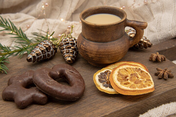 A brown ceramic mug, sweets and aromatic spices stand on a wooden tray .