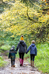 Mother and two children walking away from the camera on a muddy trail.